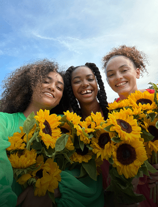 Selfie nítida e vibrante de três pessoas com flores.